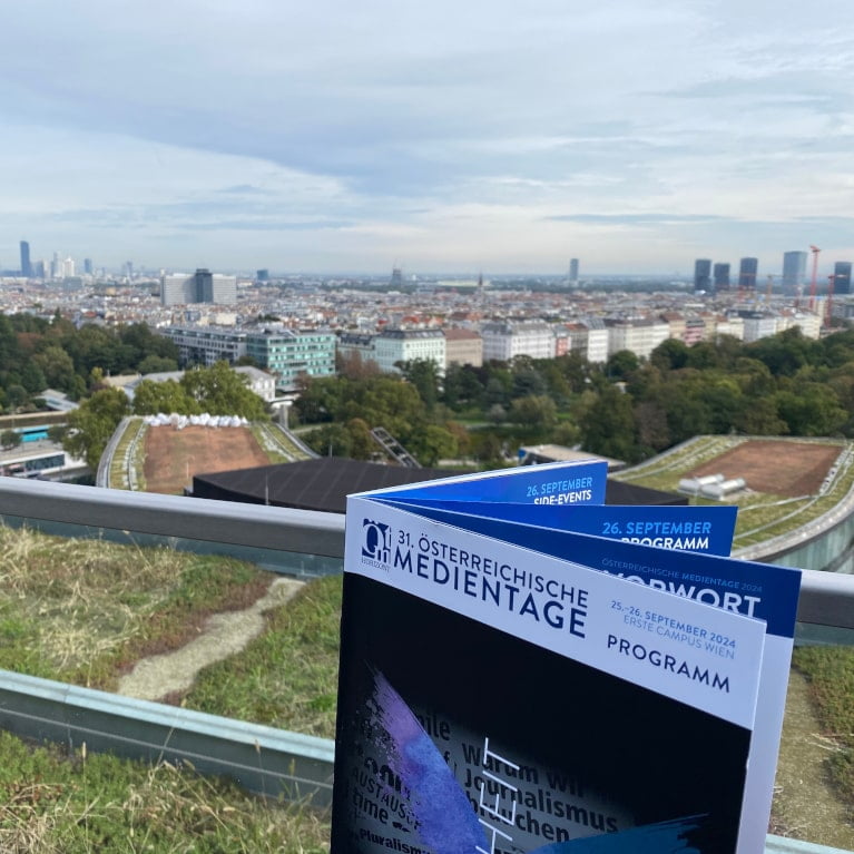 Folder der MedienTage vor den Dächern von Wien