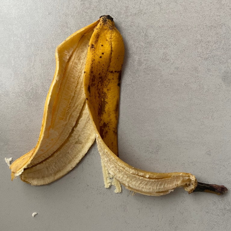 Banane, Klebeband und Schere vor grauem Hintergrund